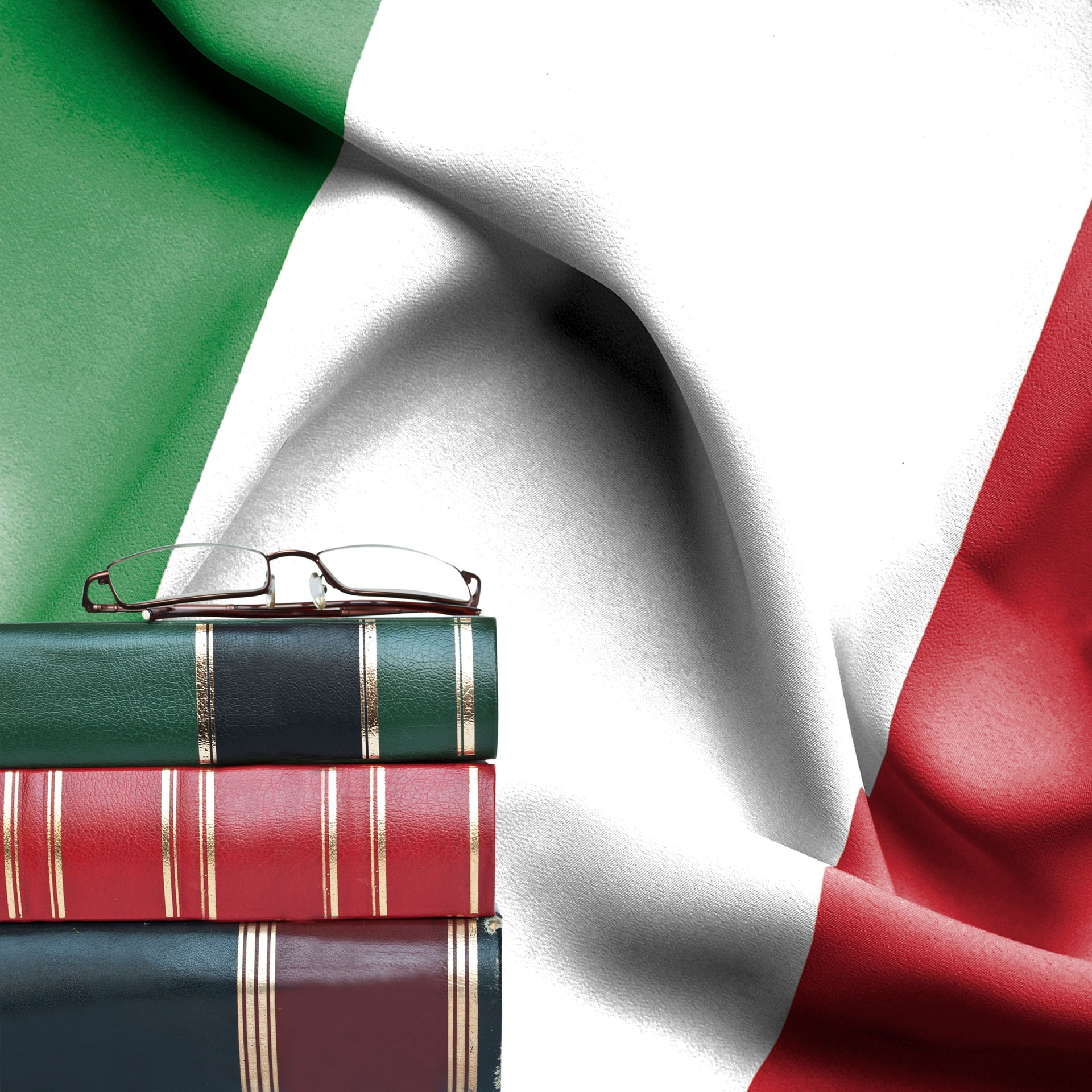 Education concept - Stack of books and reading glasses against National flag of Italy